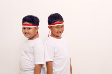 Happy asian boys standing with red white ribbon on their head. Indonesian independence day concept