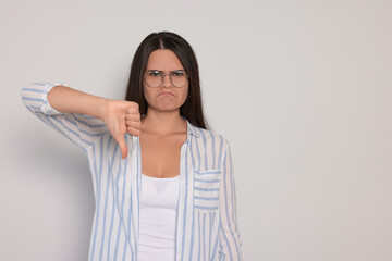 Young woman showing thumb down on white background, space for text