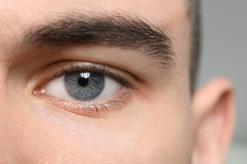 Fototapeta premium Closeup view of young man with beautiful grey eyes on blurred background
