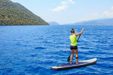 Young woman paddleboarding on a SUP board in the Mediterranean Sea. Supsurfing, Stand up paddle boarding