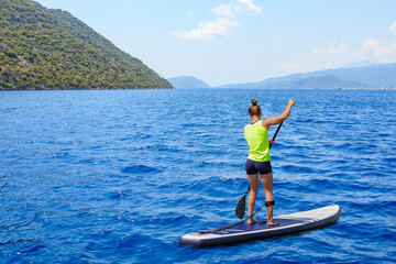Young woman paddleboarding on a SUP board in the Mediterranean Sea. Supsurfing, Stand up paddle...