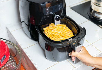 Woman hand is holding the tray of the oil free fryer machine.