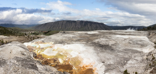 Hot spring Geyser with colorful water in American Landscape. Cloudy Sky Art Render. Yellowstone National Park, Wyoming, United States. Nature Background Panorama