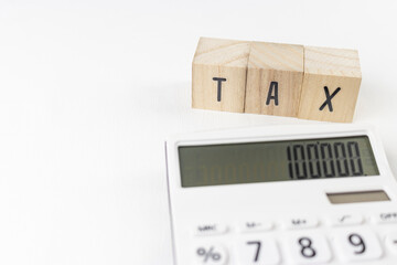 木のブロックのTAXと、電卓。税金計算のイメージ