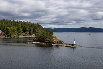Fototapeta premium Treed Island with Homes, boats and docks, nearby smaller island with lighthouse. Summer Season. Gulf Islands near Vancouver Island, British Columbia, Canada. Canadian Landscape.