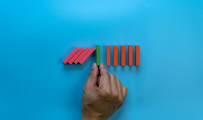 a male hand stopping the domino effect. retro style image executive and risk control concept