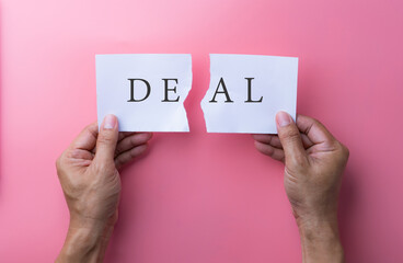 Business deal or transaction concept with the word - Deal - split over two pages of paper on different clipboards with businessmen shaking hands above them