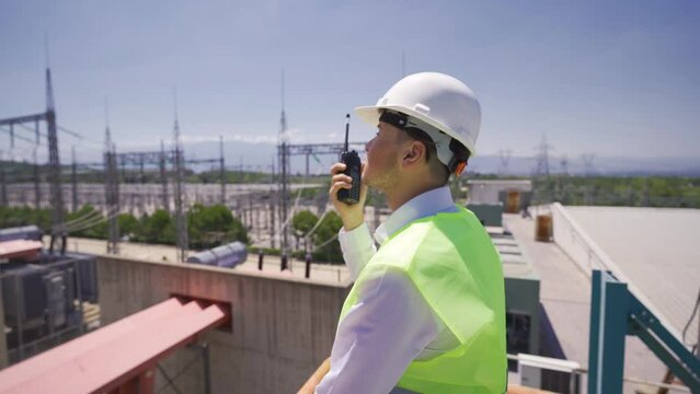 Engineer speaking by radio at power station.
The executive engineer is talking to the radio and observing the switchboard.
