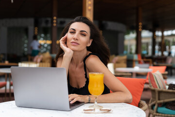 Beautiful young female freelancer working with a laptop in a street cafe