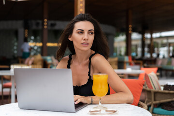 Beautiful young female freelancer working with a laptop in a street cafe