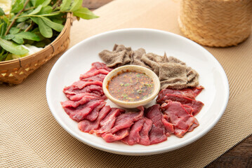 raw food ingredient. thai local food  menu soi ju, sajin, Laab, koy,soy ju , raw meat with sauce over dish on table background. 