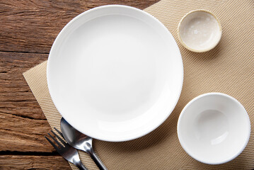 empty plate spoon fork on table. Table setting on wooden table background