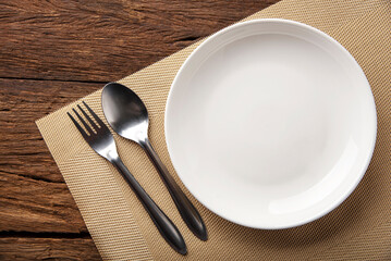 empty plate spoon fork on table. Table setting on wooden table background