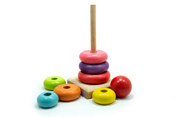 Pyramid toy is made of colored wooden rings with funny heads on top of toys for babies on a white background.