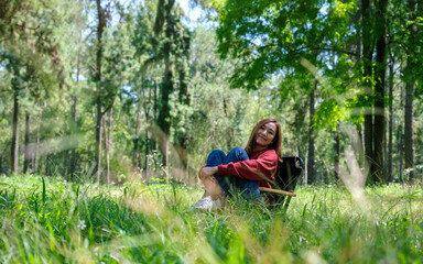 Portrait image of a beautiful young asian woman sitting and relaxing on a chair in the park