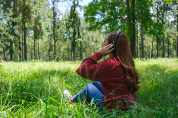 Fototapeta premium Portrait of a beautiful young asian woman enjoy listening to music with headphone while sitting in the park