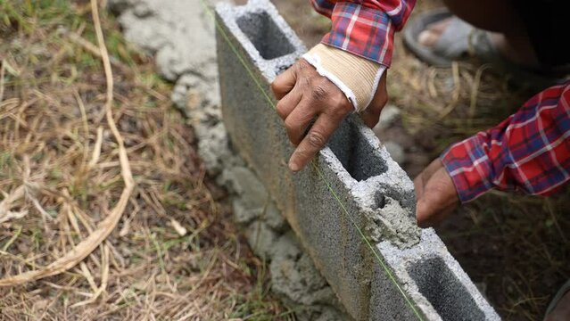 Builder laying a wall of gas blocks with tools and adhesive mortar. Construction from ACC blocks. A worker builds an inner wall of a house from aerated concrete bricks.