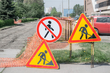 road signs of the ongoing repair work of the sidewalk on a city street against the background of...