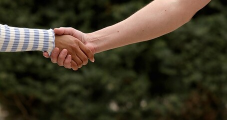 A male close up holding a hand between two colleagues who have a good relationship concept in a natural background.