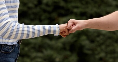 A close up image of a fist bump man and woman outdoor. Friendship concept.