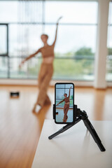 Smartphone filming professional dancer moving to music in studio