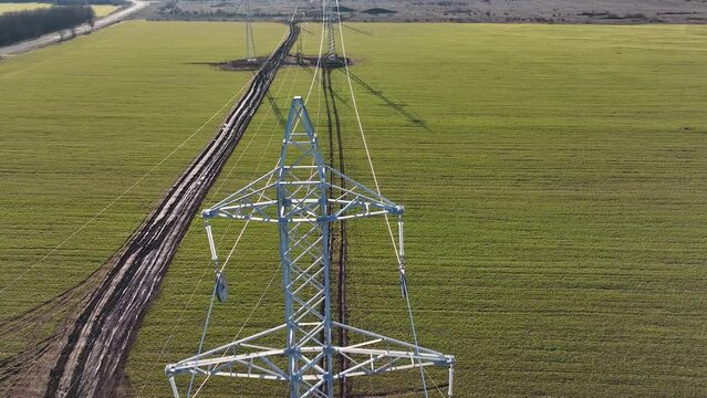 Aerial circling view of steel erector workers strengthen a newly installed power line pylon. Transmission tower or power tower
supporting an overhead high voltage power line. The pylon carries wires
