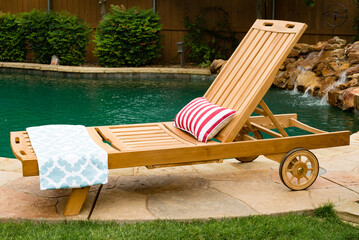 Wood chase lounge chair on a pool deck with swimming pool in the background. - obrazy, fototapety, plakaty
