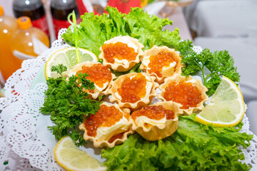 Red caviar and grated cheese in small dough baskets. A delicious cold appetizer with seafood. Close up