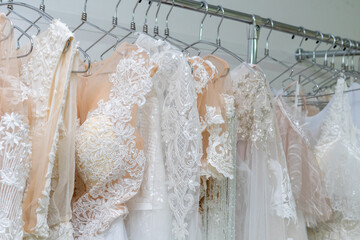 White and cream wedding dresses on a hanger in a bridal boutique. Close up