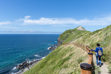 神威岬への遊歩道を歩く女性の後ろ姿と海
