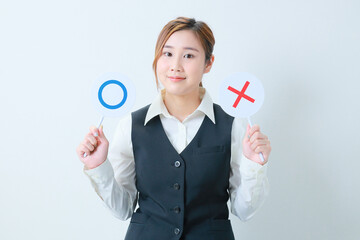 ○✖プレートを持って微笑む若いOL