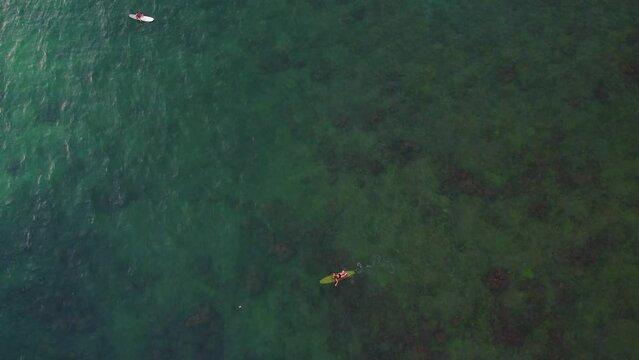 Surferzy w oceanie czekający na fale, aktywny wypoczynek, tropikalny krajobraz, ujęcie z drona.