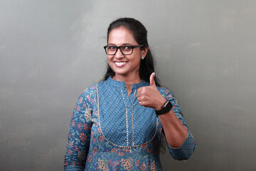 Portrait of a smiling woman of Indian ethnicity showing thumbs up sign