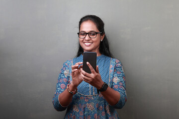 Fototapeta premium Smiling woman of Indian ethnicity looking at her mobile phone