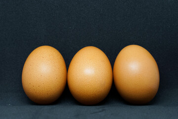fresh chicken eggs laid out on a black background.