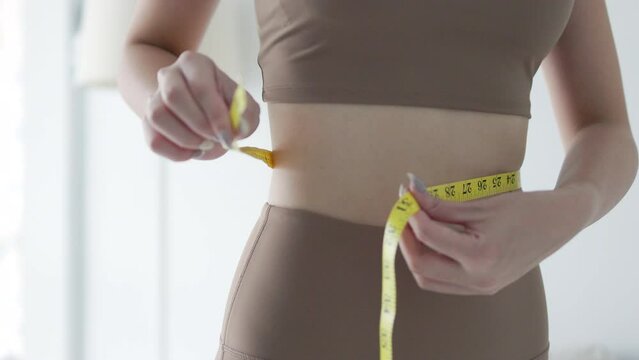 girl holding measuring tape around her in fit sportswear
