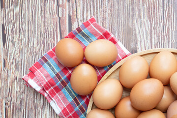 Top view of Chicken eggs in bowl and three eggs on red plaid fabric are on table