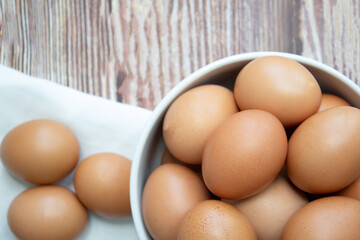 Top view of Chicken eggs in bowl and three eggs on fabric are on table