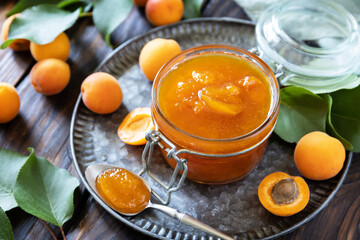 Homemade preservation. Delicious apricots jam or jelly on a rustic wooden table.