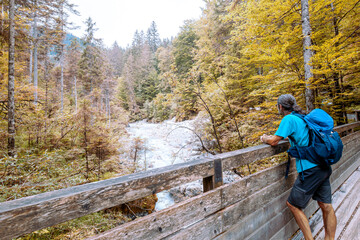 Man standing at the Bridge, hiking in forest in the Wimbachtal in Germany. Enjoying the silent. 