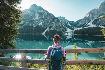 Fototapeta na wymiar Young woman enjoys amazing view on Braies Lake in Dolomites mountains in the morning. Braies Lake (Pragser Wildsee, Lago di Braies), Dolomites, South Tirol, Italy, Europe.