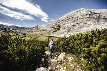 Young woman is hiking on beautiful trail from Baires Lake to Seekofel in the Dolomite mountains in the morning. Seekofel, Dolomites, South Tirol, Italy, Europe.