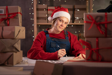 Small business owner in santa hat taking order online at home office at night, christmas delivery...