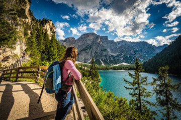 Young woman enjoys beautiful view on Baires Lake in the Dolomite mountains in the afternoon. Braies...