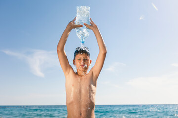 The boy is having fun on the beach, getting splashed with water.