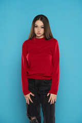 Cute girl in red blouse and black jeans isolated on blue background
