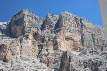 Fototapeta premium Val Badia, Italy-July 17, 2022: The italian Dolomites behind the small village of Corvara in summer days with beaitiful blue sky in the background. Green nature in the middle of the rocks.
