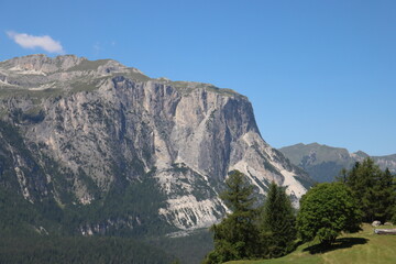 Val Badia, Italy-July 17, 2022: The italian Dolomites behind the small village of Corvara in summer days with beaitiful blue sky in the background. Green nature in the middle of the rocks.