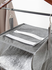 Small grey hanging organizer for clothes on white wall background. Storage system for wardrobe. Hooks closeup