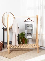 Grey hanging organizer for clothes and bathrobe on wooden floor hanger. Storage system for wardrobe - obrazy, fototapety, plakaty